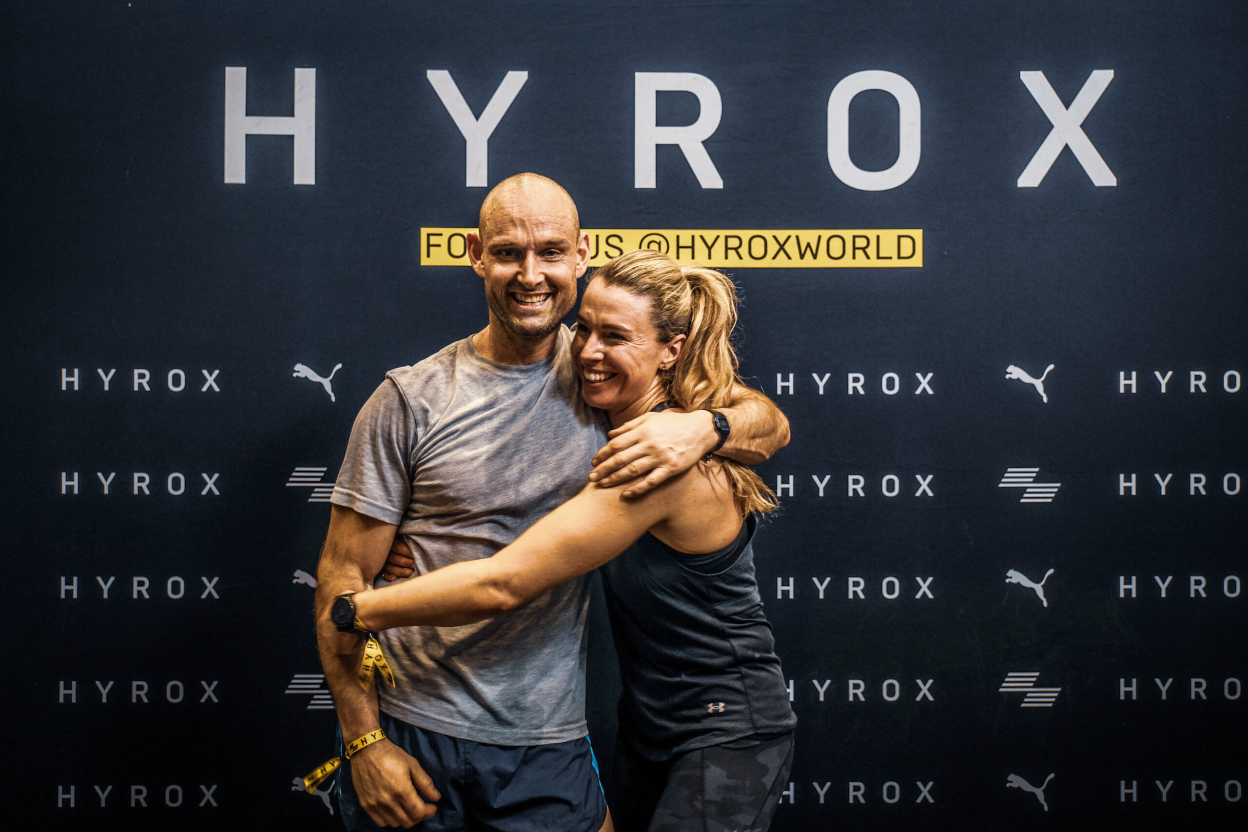 HYROX-Athlet im Zieleinlauf, sichtbar erschöpft aber stolz – echtes Wettkampffeeling pur.