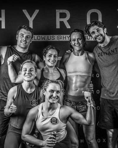 Glückliche HYROX-Teilnehmer nach dem Rennen, Arm in Arm und voller Stolz im Zielbereich.